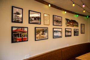 Framed vintage photos displayed on a restaurant wall with decorative string lights in a cozy dining area.