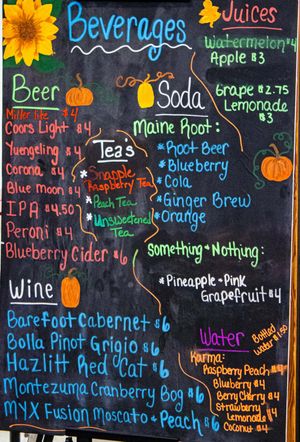 Chalkboard beverage menu listing beers, wines, sodas, teas, juices, and water with prices at a food or drink stand.