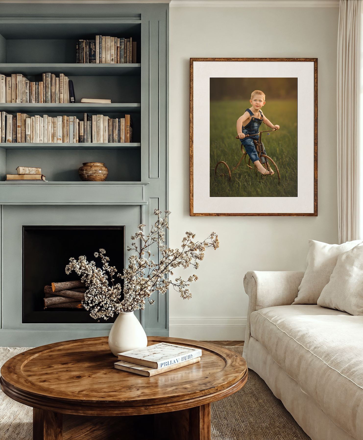 Cozy living room with blue built-in bookshelf, round wood coffee table, and framed child portrait above fireplace.