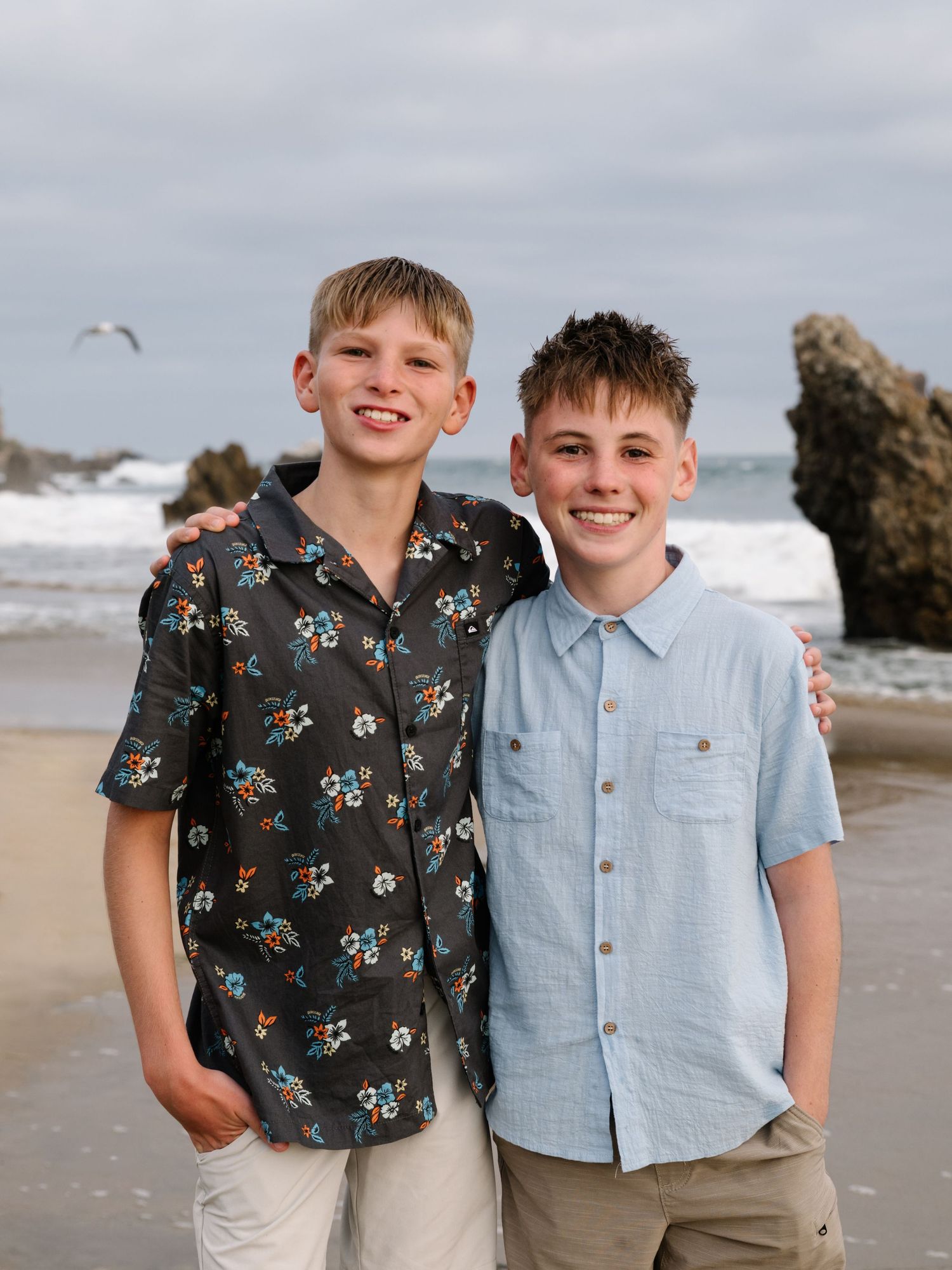 Two teenage boys standing together for a portrait on the beach during an Orange County family photography session.