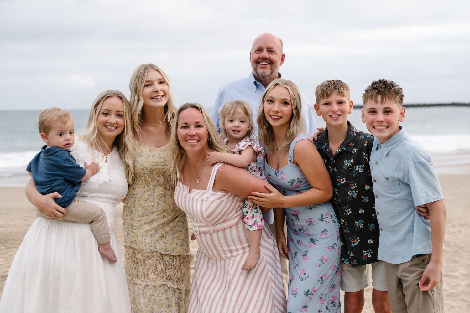 Multigenerational family smiling together on the beach during a Newport Beach extended family photography session.