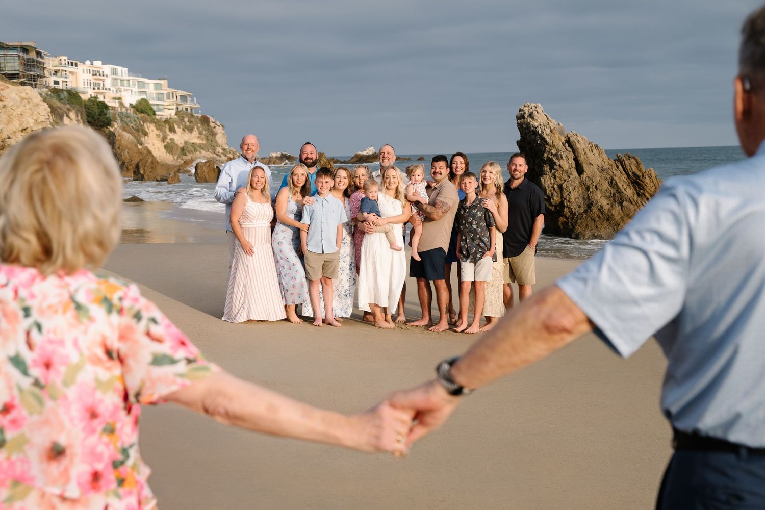 Family members smiling at grandparents on the beach during a relaxed Newport Beach extended family photography session.