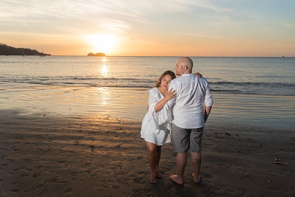 Elderly couple dancing romantically on a sandy beach at golden sunset, waves gently lapping the shore behind them.