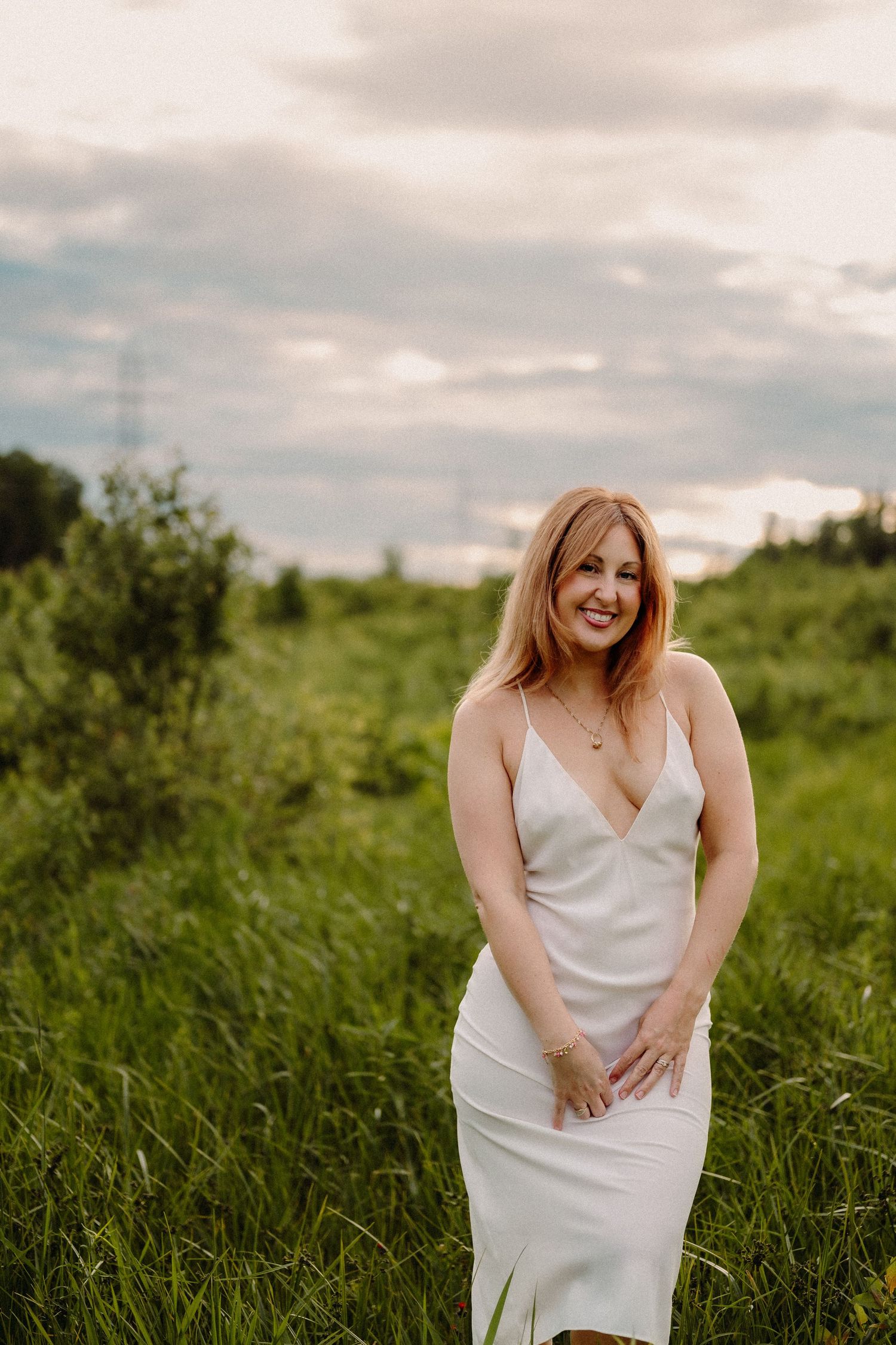 Expecting mother in a blue dress poses on a sunlit nature path.