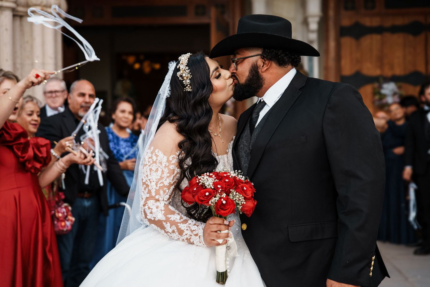 Bride in white lace gown holding bouquet shares tender moment with mother in beige lace dress at wedding.