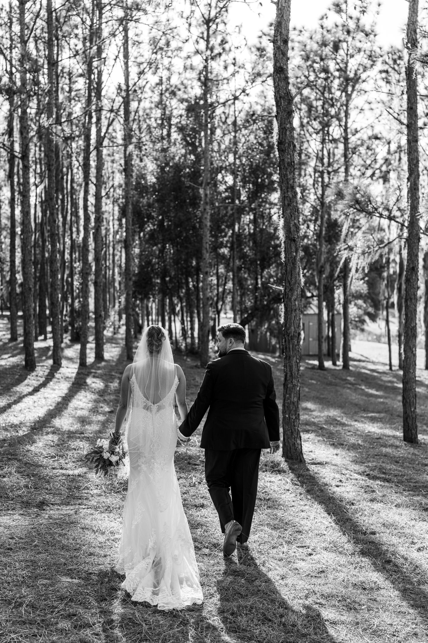 Black and white photo of a couple kissing, reflected in a vintage car mirror on a scenic road.