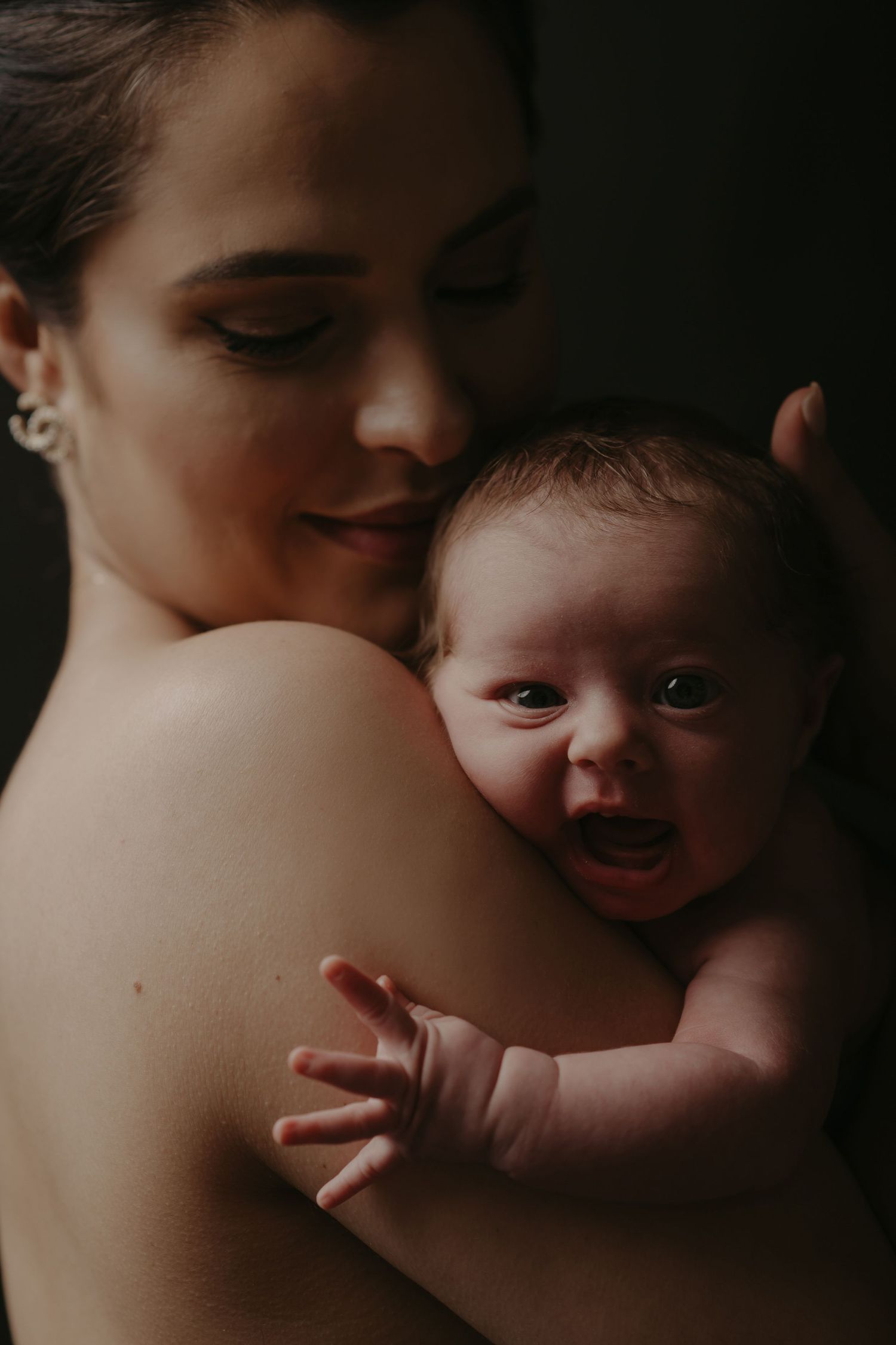 Tender moment between parent and smiling baby during intimate portrait session.