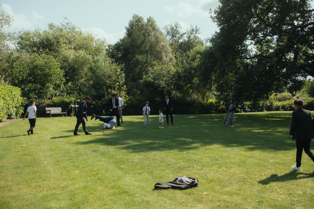 Family playing cricket on the lawn of a wedding venue at Winstanley house, Warwick, UK