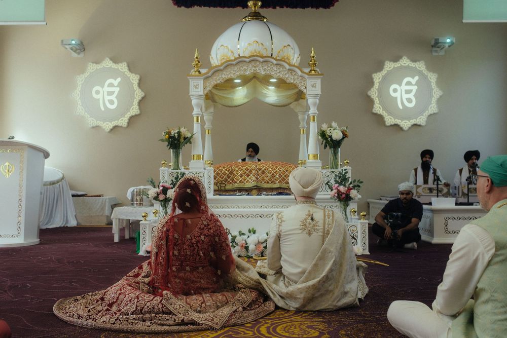 Indian, sikh, fusion bride and groom during their wedding ceremony in a gurdwara in the UK.