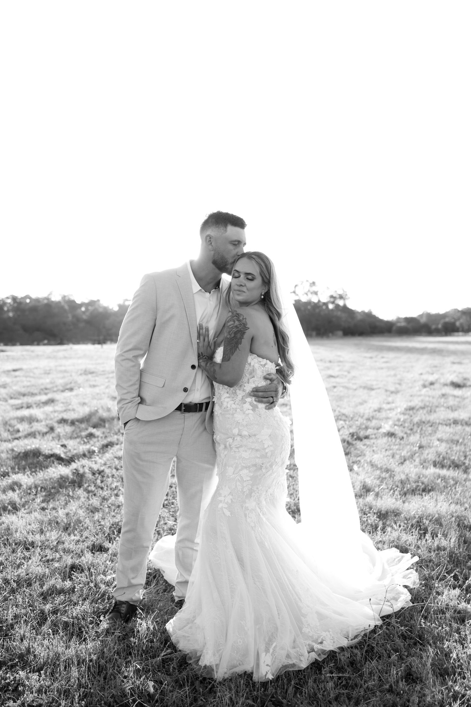 A romantic black and white wedding photo series showing a couple embracing in a sunlit meadow.