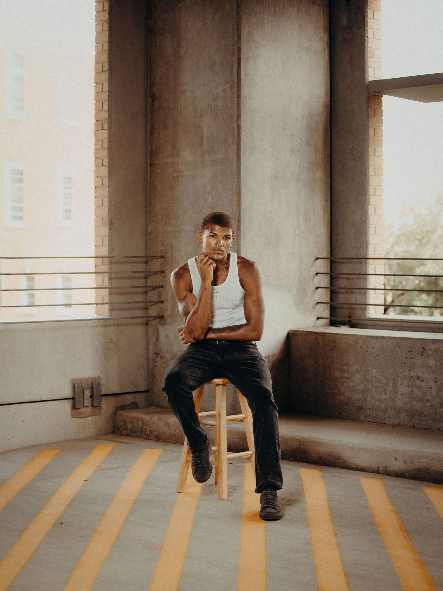 Editorial portrait of a man seated on a stool in an industrial setting