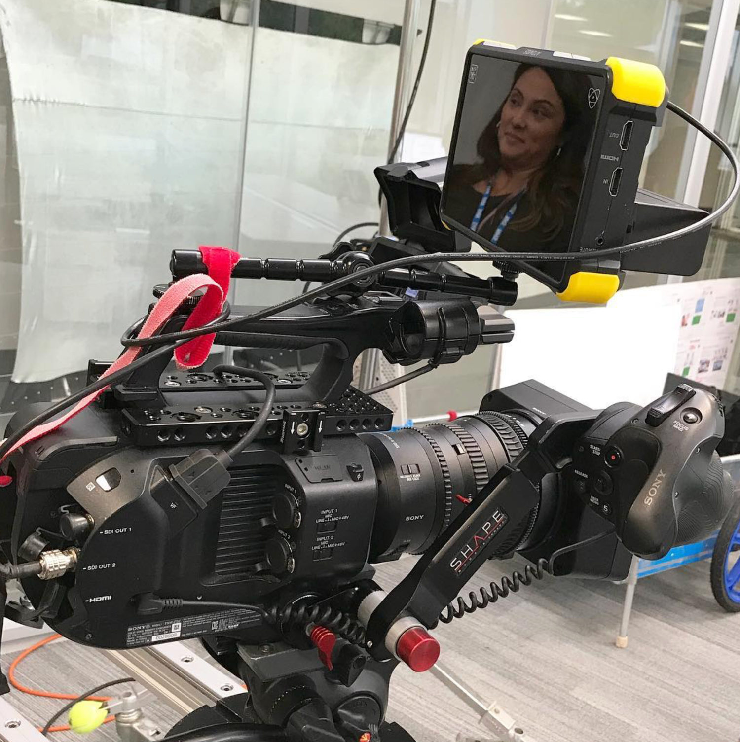 Professional video camera rig with monitor showing a woman's reflection in a modern studio setting.