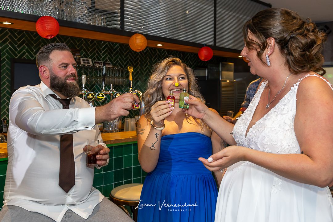 Even tijd voor een shotje, flugel, bruid, bruideom en getuige, tijdens de feestavond