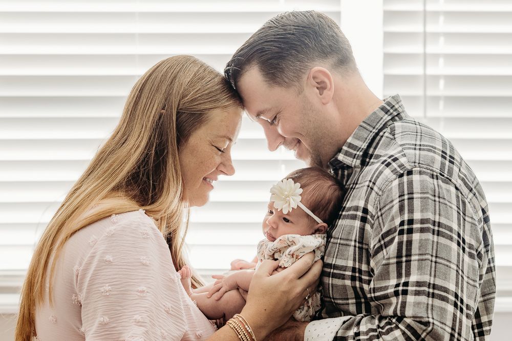 Parents cuddling their newborn daughter during a Cherry Hill lifestyle newborn photography session.
