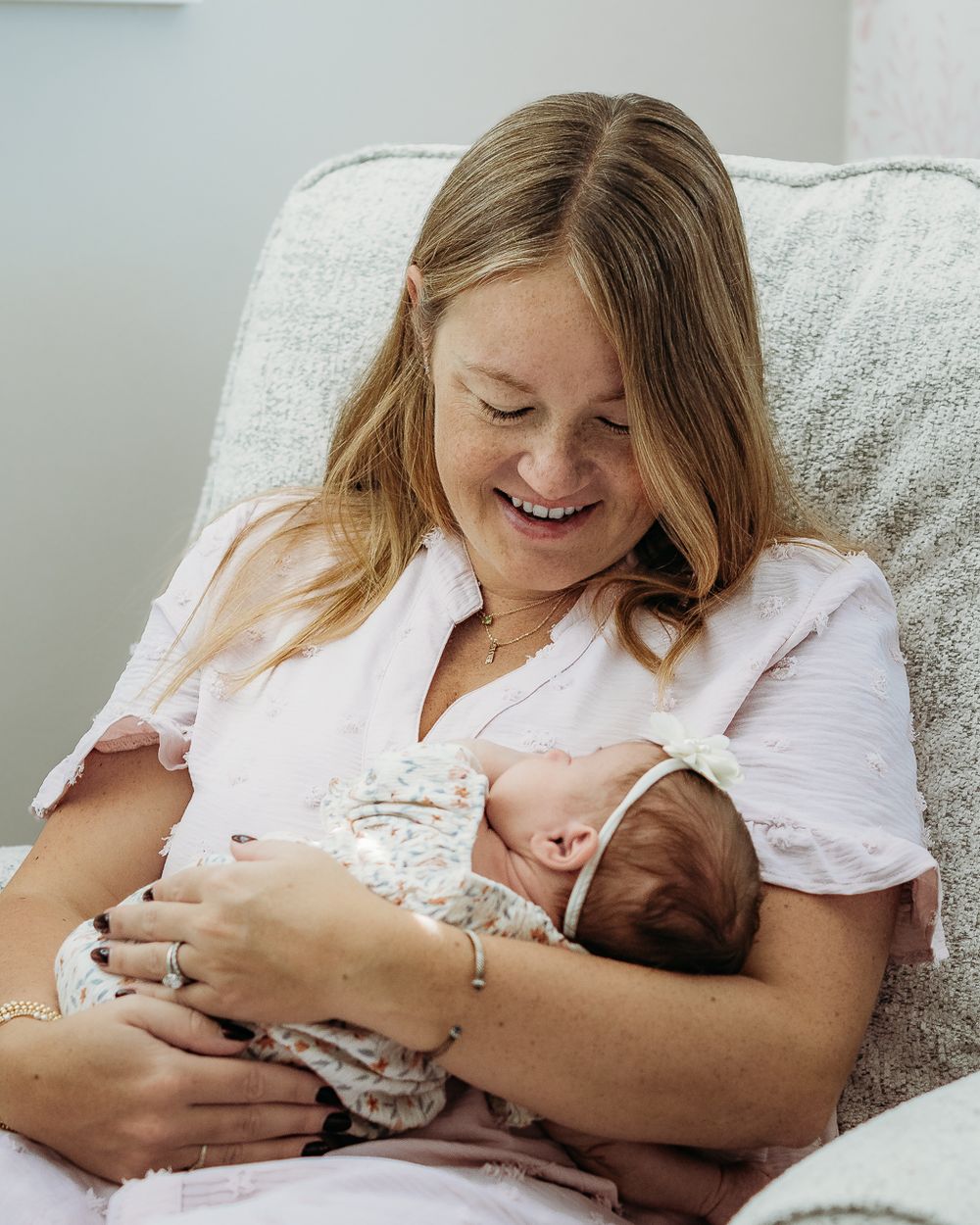 Mother smiling while cuddling her newborn baby during an in-home South Jersey newborn session.