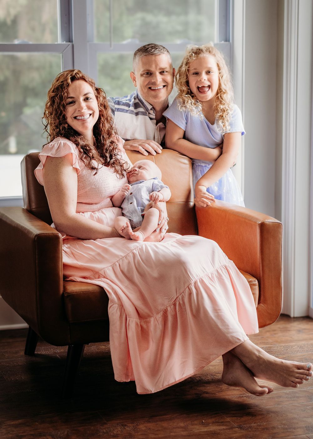 Family of four cuddling their newborn baby during an in-home South Jersey newborn session.