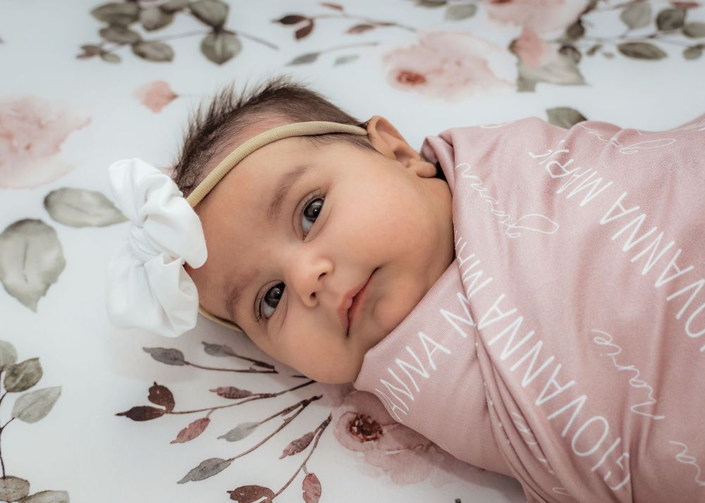 Newborn baby girl lying on a floral blanket during a South Jersey newborn photography session.