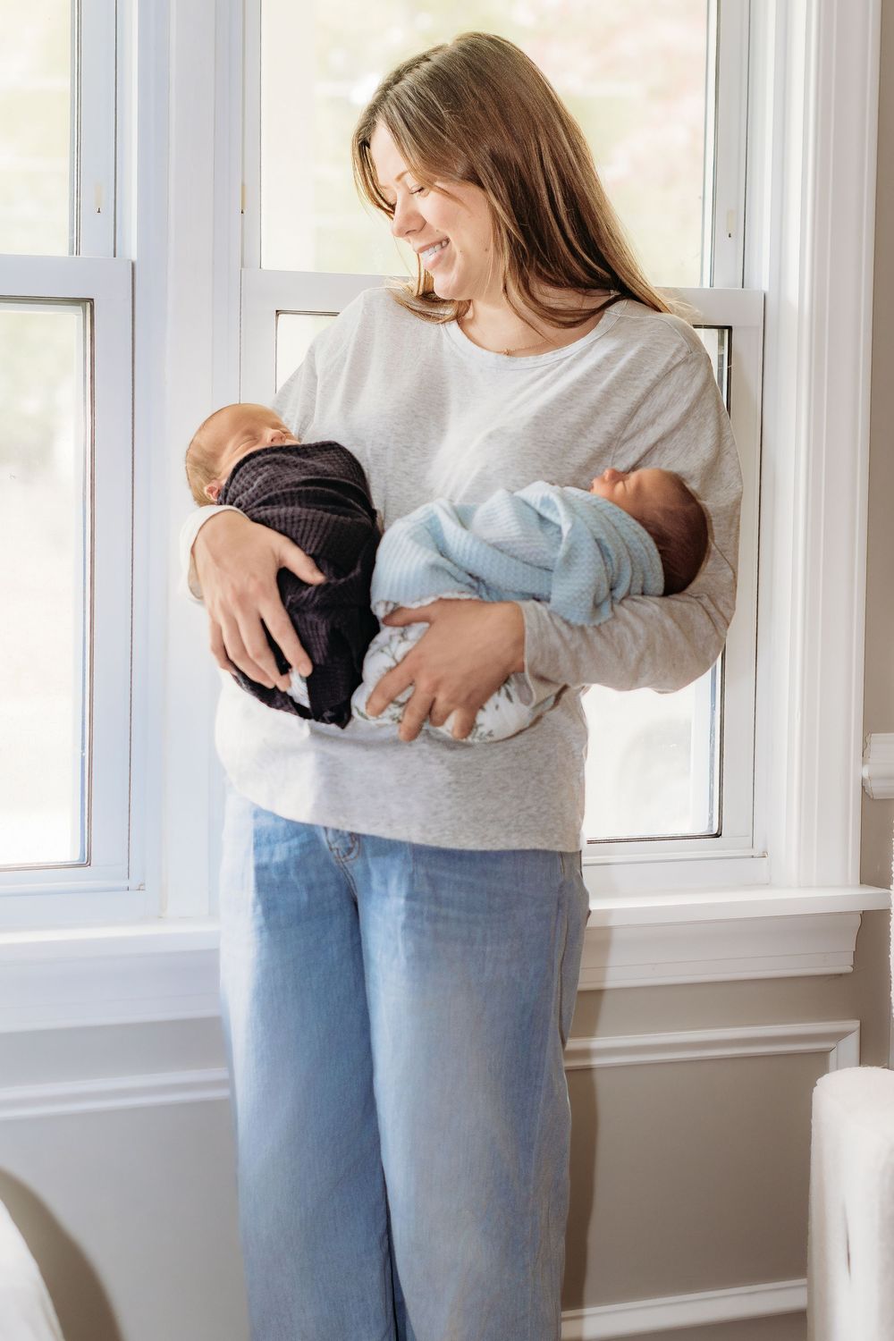 Mother holding newborn twins during a South Jersey lifestyle newborn photography session.