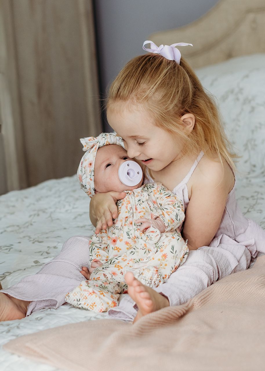 Big sister cuddling her newborn baby sister during an in-home West Deptford newborn session.