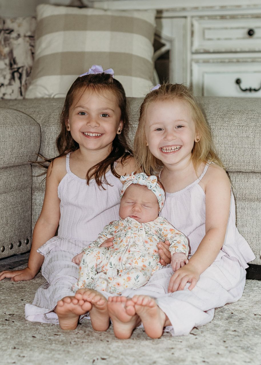Three sisters cuddling together during an in-home South Jersey newborn photography session
