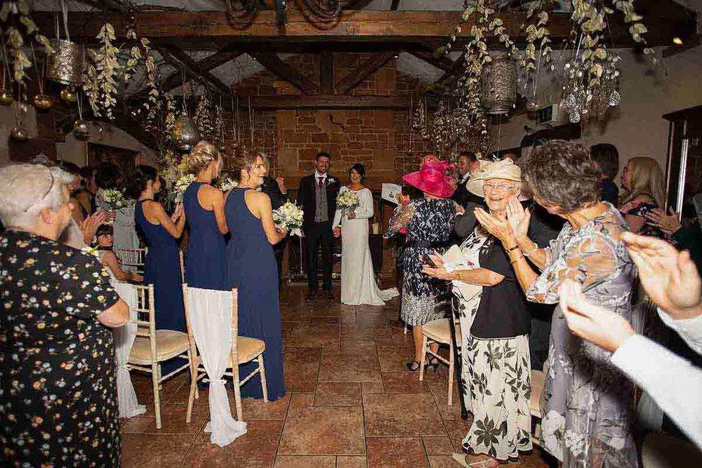 Bride walks down the aisle at rustic barn wedding venue at Skitby House wedding venue near Longtown