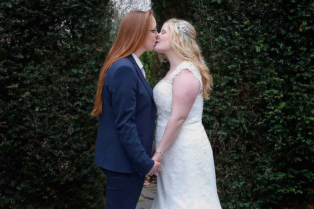 Two brides sharing a kiss on their wedding day in the grounds of Skitby House wedding venue