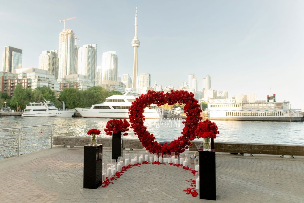 Heart-shaped red rose arch proposal setup with CN Tower and Toronto waterfront skyline.