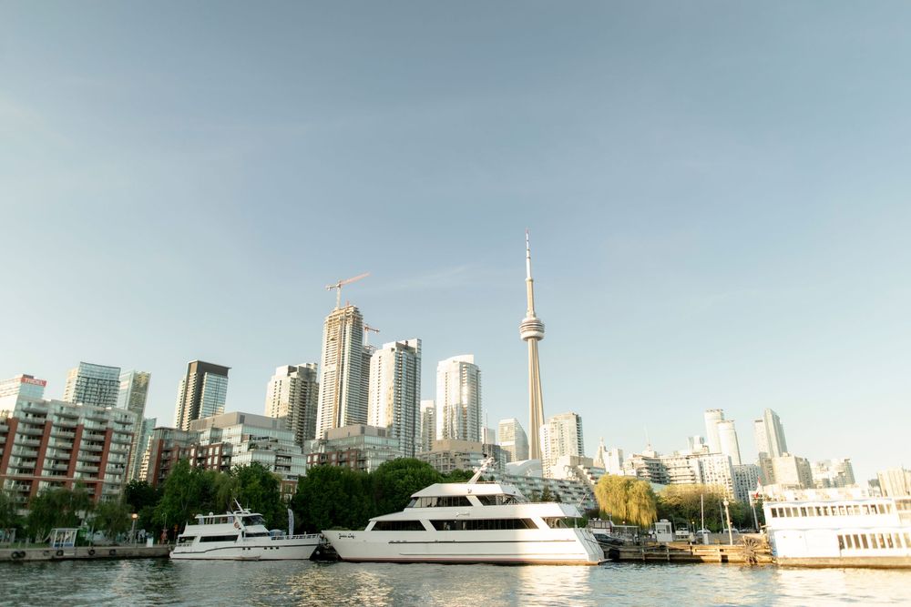Toronto skyline with CN Tower viewed from waterfront with luxury yachts docked on a clear day.