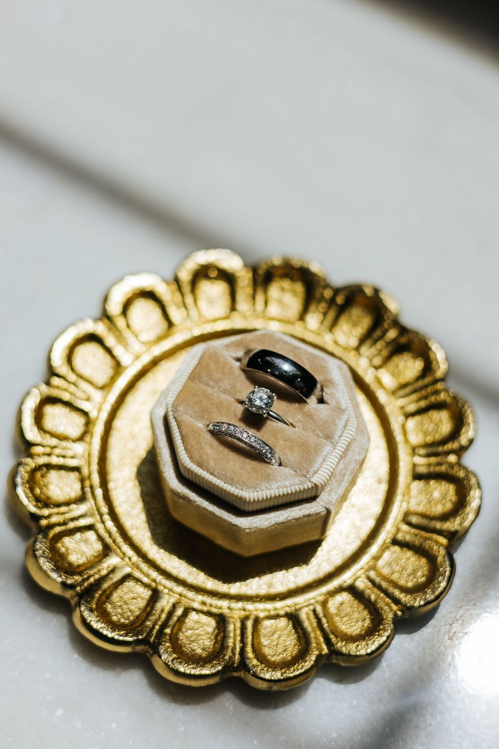 Wedding rings displayed in velvet box on ornate gold decorative plate.