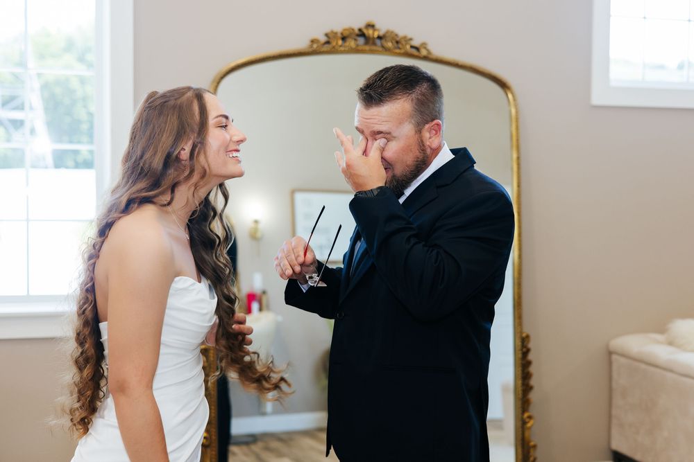 Emotional father wiping tears seeing bride daughter before wedding ceremony.