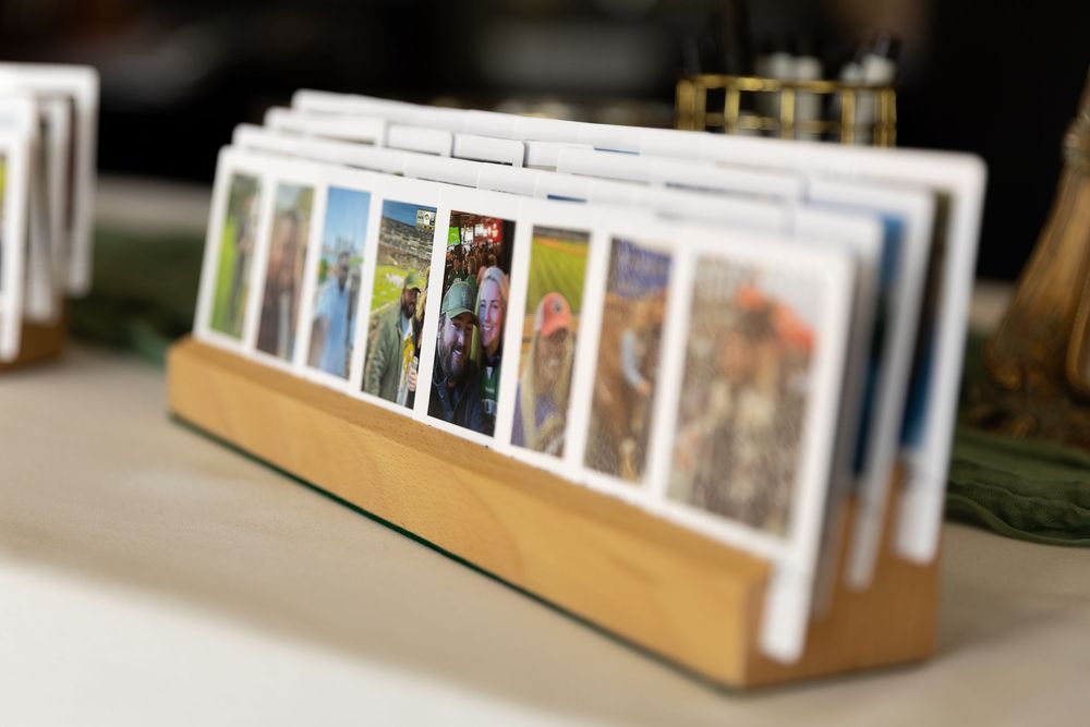 A wooden photo display stand holding a row of colorful printed photographs on a table.