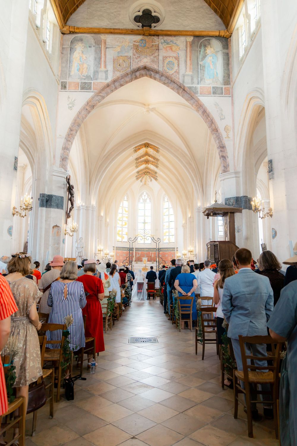 Guests standing in rows inside a grand Gothic church with vaulted ceilings during a wedding ceremony.