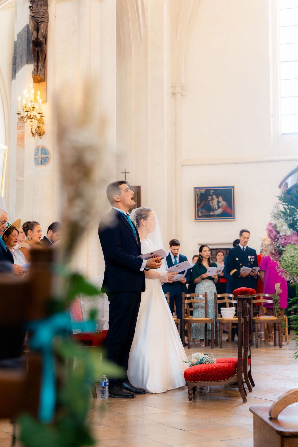 Bride and groom standing at church altar during wedding ceremony with guests seated in pews behind them.