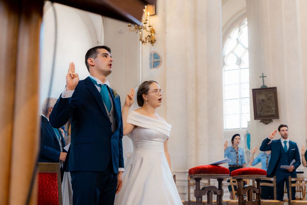 Bride and groom exchanging vows at a church wedding ceremony, with guests seated in pews in the background.