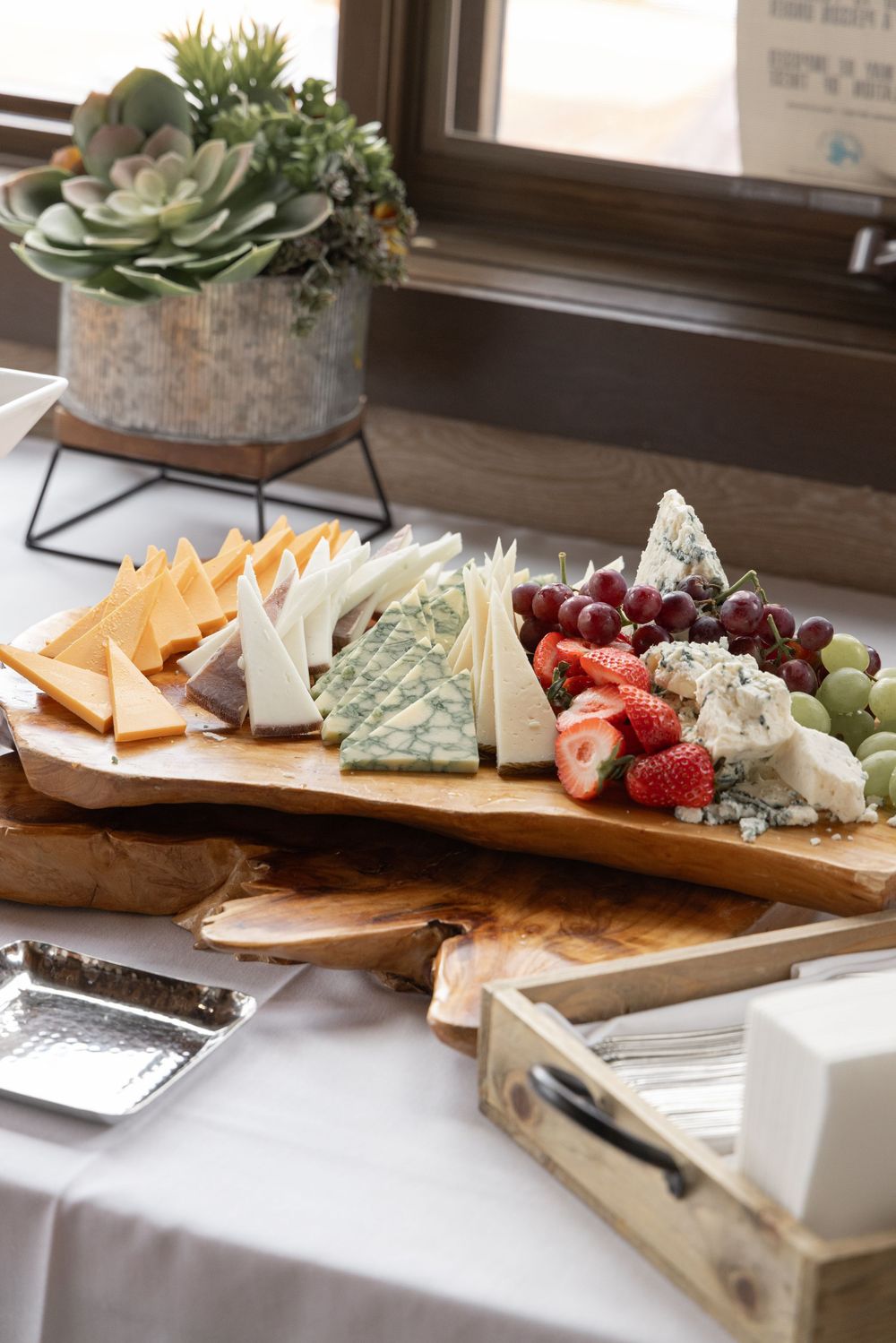 Elegant charcuterie board with assorted cheeses, fresh strawberries, and grapes on a rustic wood platter for entertaining.