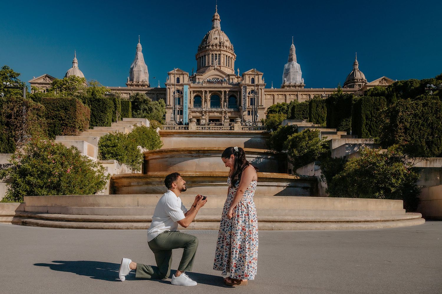Candid couple walking hand-in-hand past the grand stone columns of the Montjuic palace axis