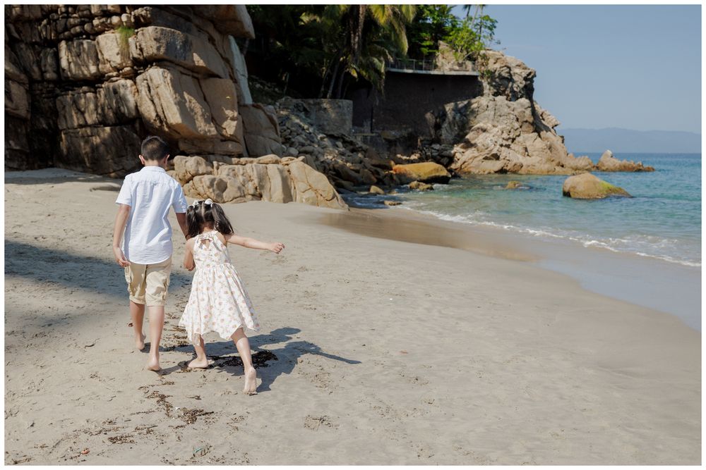 Hyatt Ziva Puerto Vallarta Family Photographer capturing children walking hand in hand along the beach during Lifestyle Family Photography