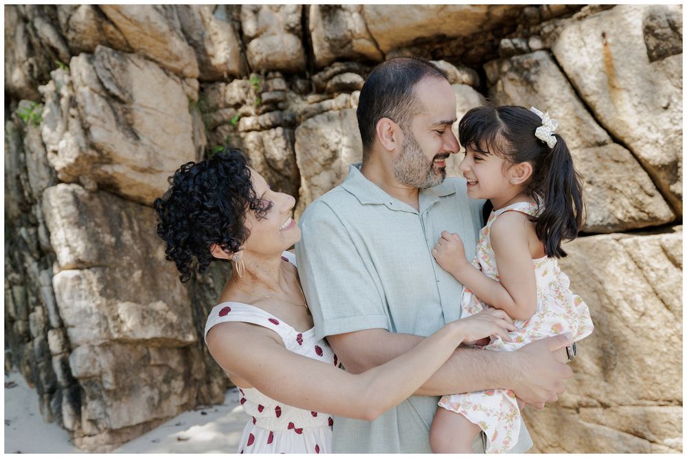 Hyatt Ziva Puerto Vallarta Family Photographer capturing parents embracing their daughter on the beach during Family Photo Session.