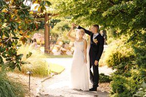 Bride and groom dancing on a garden path surrounded by lush greenery on their wedding day.