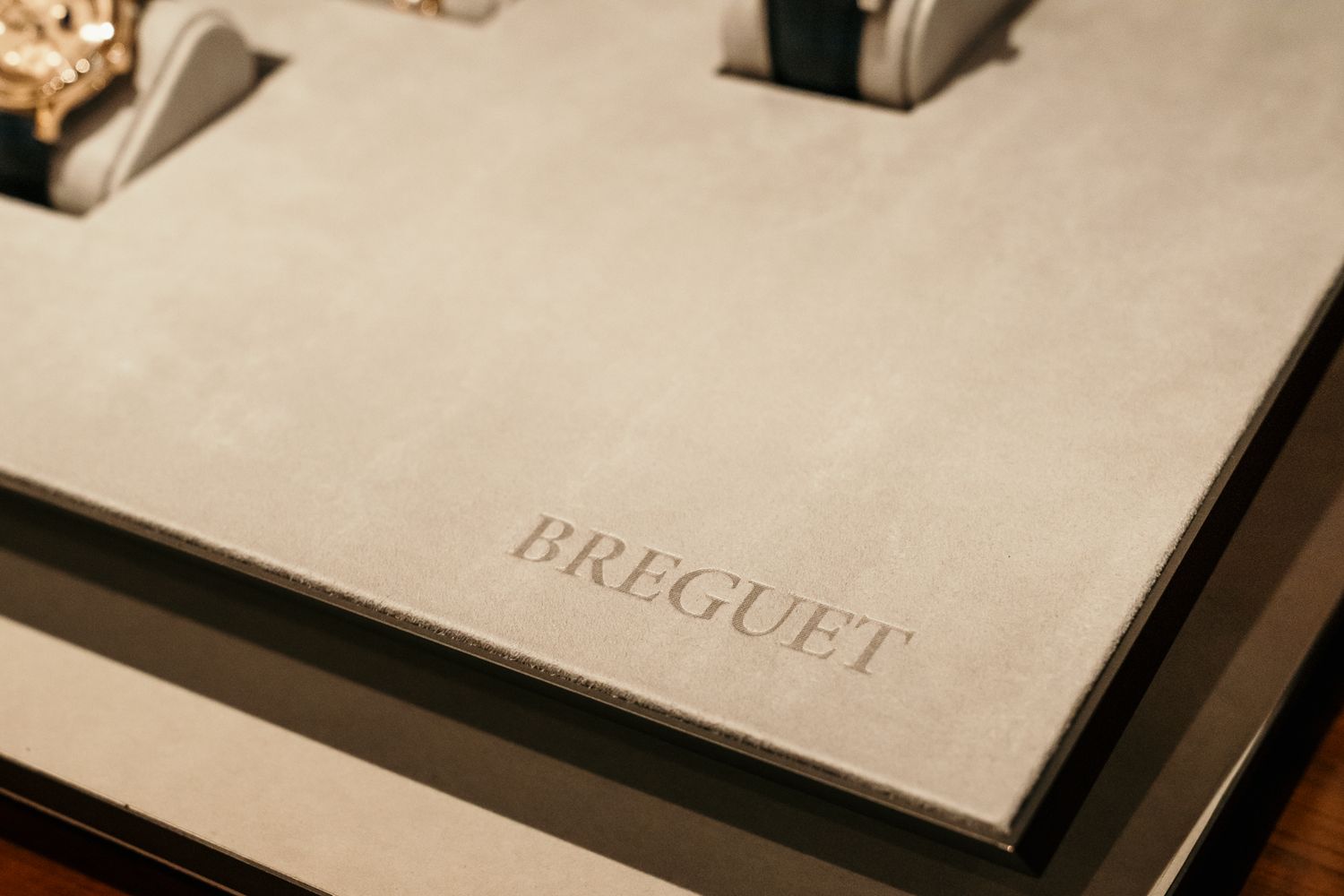 Breguet luxury watch display case with embossed brand name on beige suede surface.