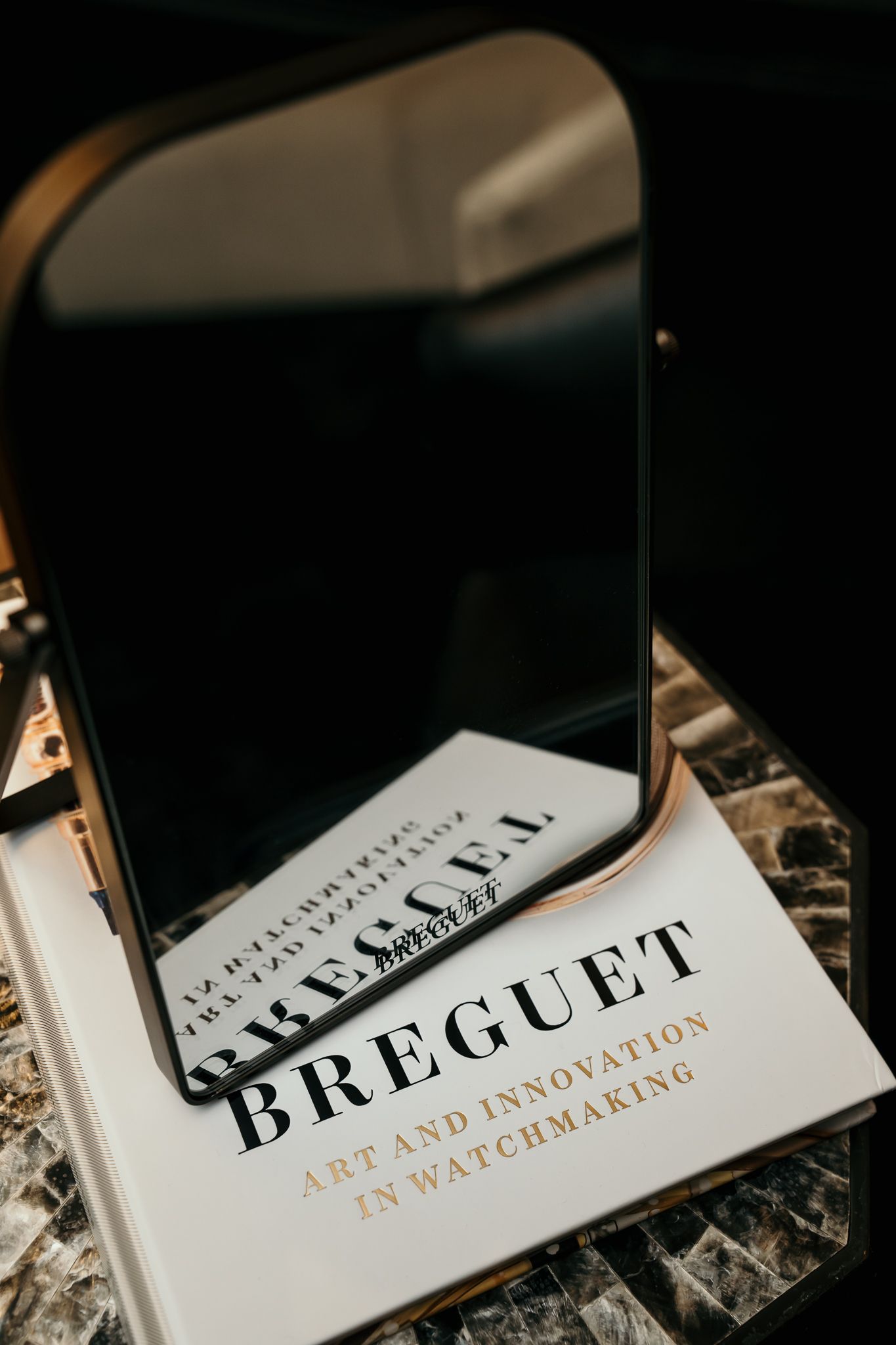 Breguet Art and Innovation in Watchmaking book displayed with a small mirror on a marble surface.