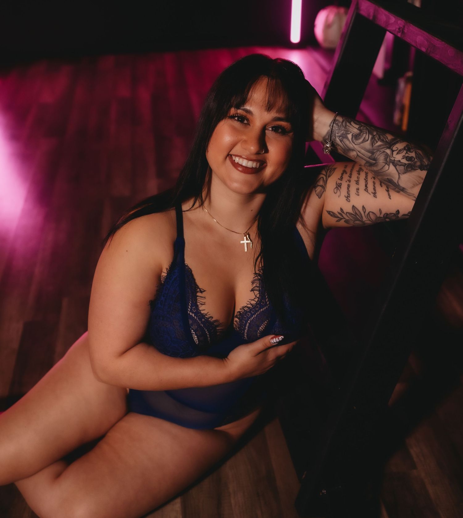 woman smiling as she is being posed for her boudoir session in tampa florida. She is wearing blue lace lingerie