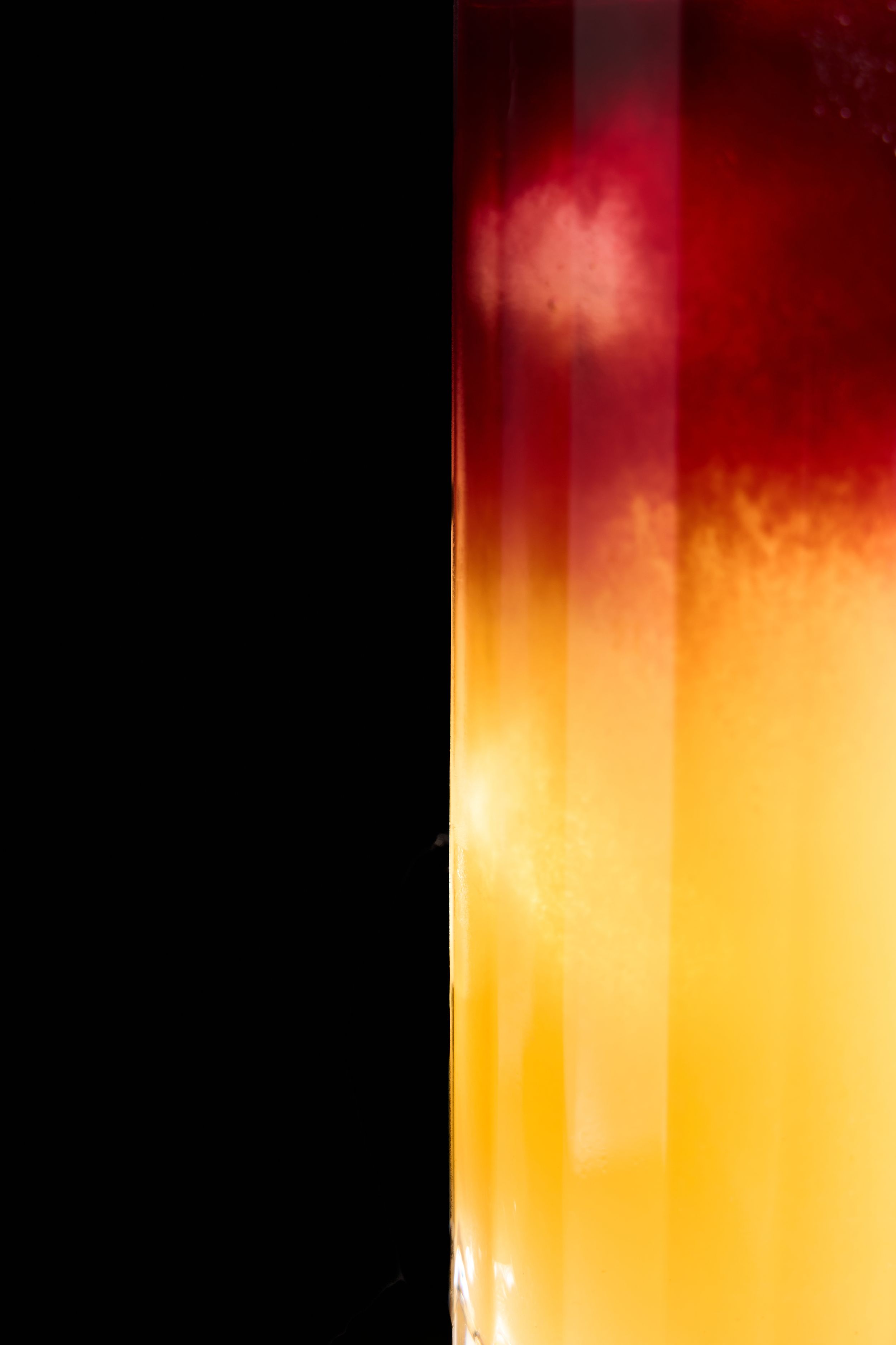 Abstract art with vivid red and yellow gradient blending against a stark black background, creating a dramatic fiery effect.