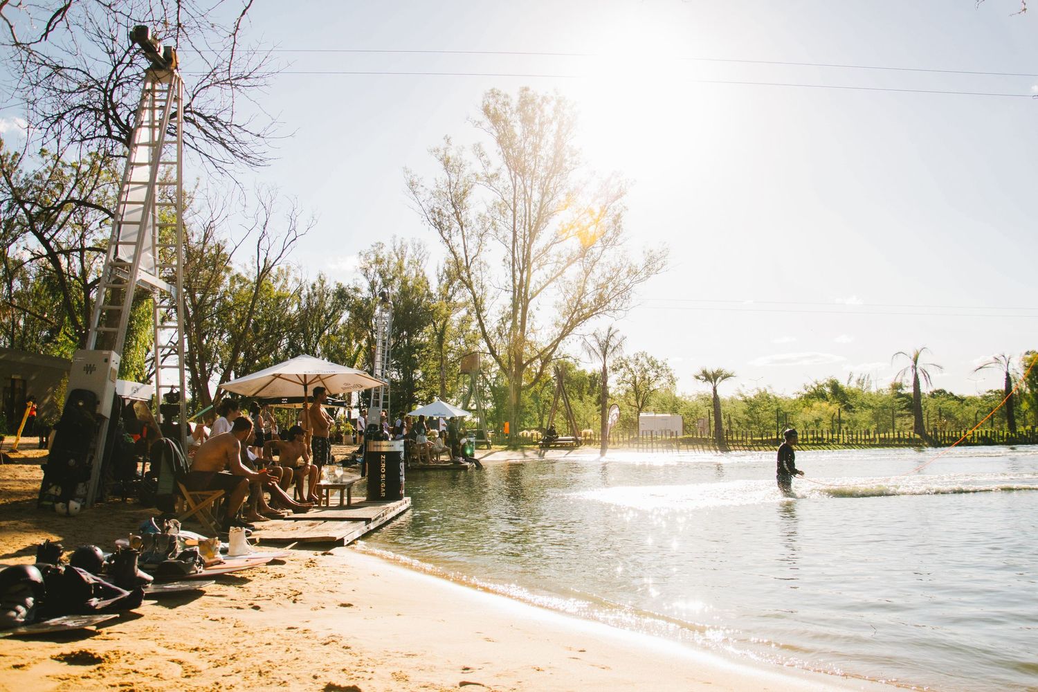 Person wakeboarding on a sunny lake at a beachside outdoor event venue.