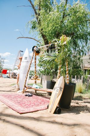 Billabong surfboards and beach decor display with red rug and tropical plants at outdoor event.