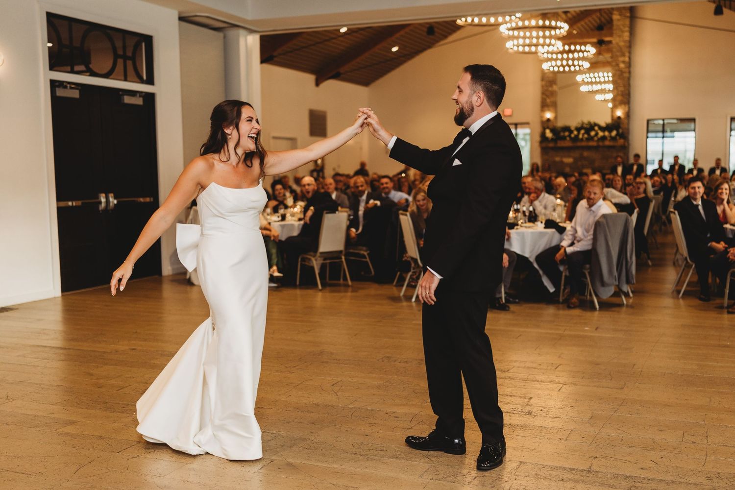 Bride and groom share first dance in elegant reception hall with guests.