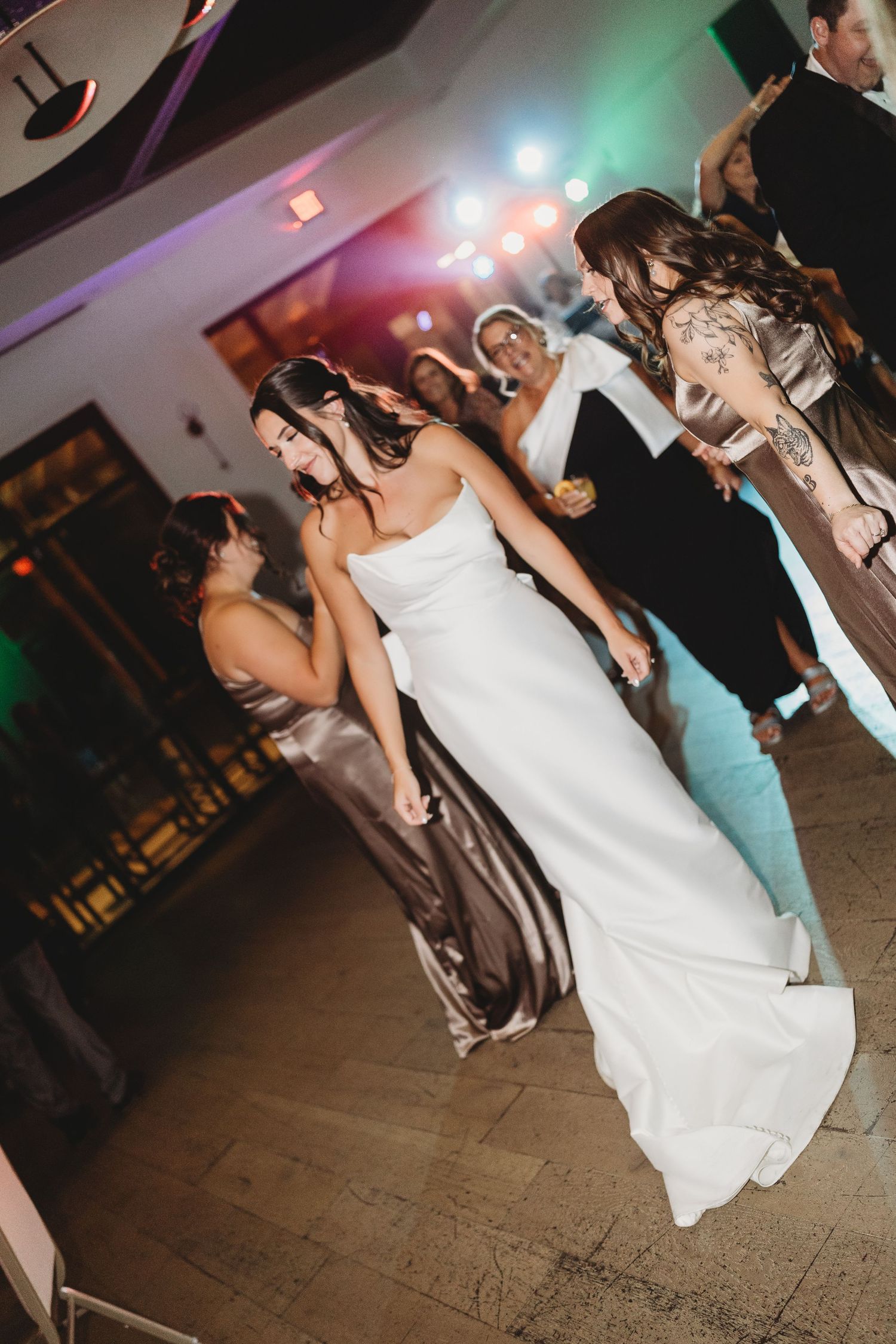 Bride dancing with bridesmaids at colorful wedding reception.