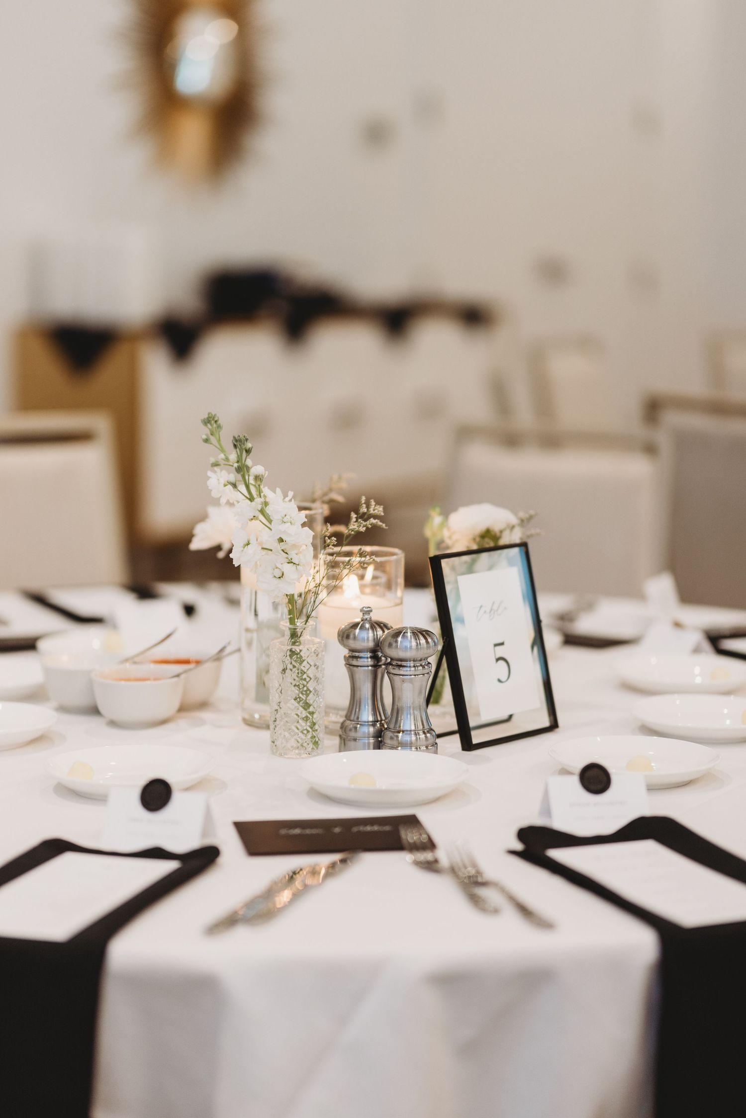 Elegant black and white wedding reception table setting with floral centerpiece and framed table number.