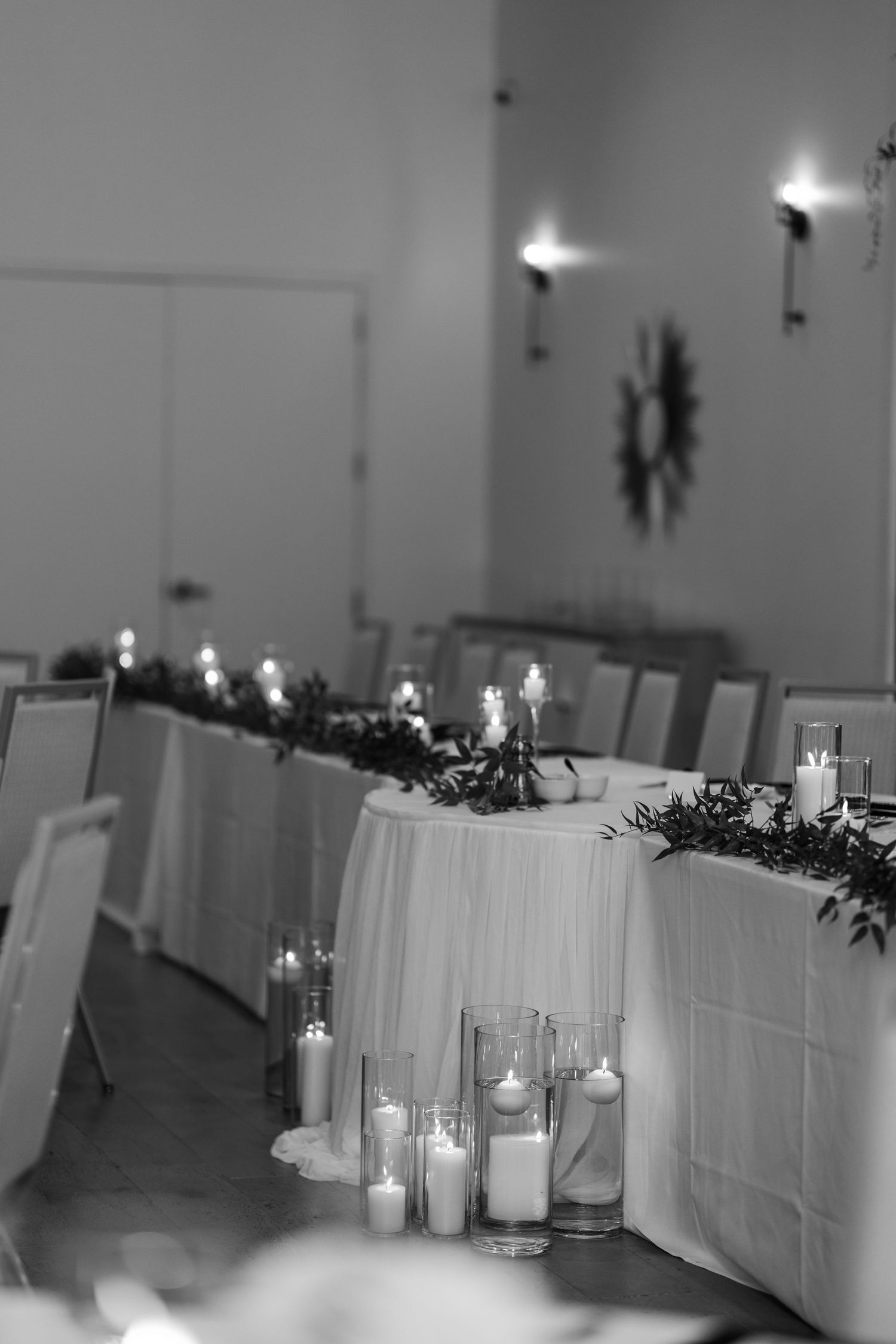 Elegant black and white wedding reception table with candles and greenery garland.