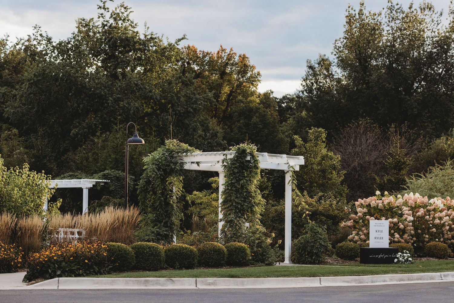 Elegant white garden pergola covered in lush greenery at a scenic outdoor wedding venue.